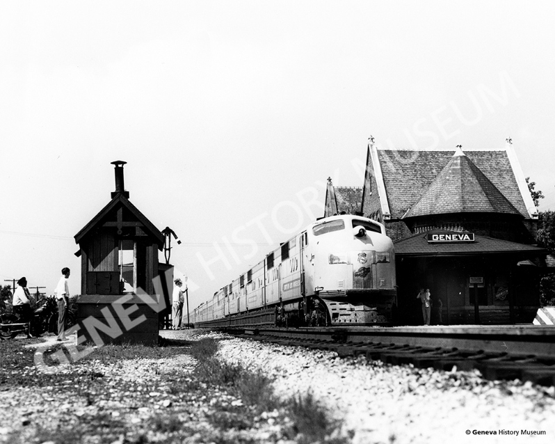 Product Description: Circa 1950s - Commuter train pulling into the Geneva Train Depot. The Victorian style depot was built in 1892 and was demolished in 1960. In 1986, the present day depot was designed and contructed to echo the 1892 station.</br></br>Available sizes:</br></br>8 x 10 = $20.00; 11 x 14 = $30.00; 16 x 20 = $40.00; 20 x 30 = $55.00; 24 x 36 = $65.00</br></br>In-store pickup free. Shipping available.</br> No. 12 - Geneva Train Depot - Circa 1950s